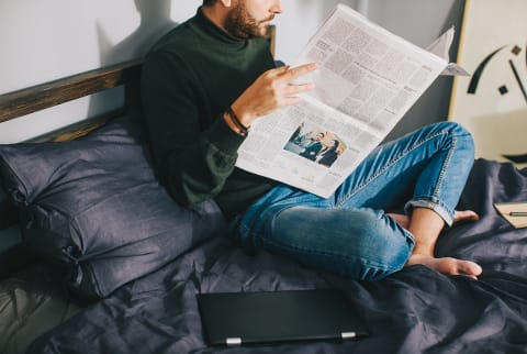 Unrecognizable Man Reading the Newspaper in Bed