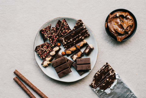 verhead view of chocolates bars pieces and chocolate cream on a cement background